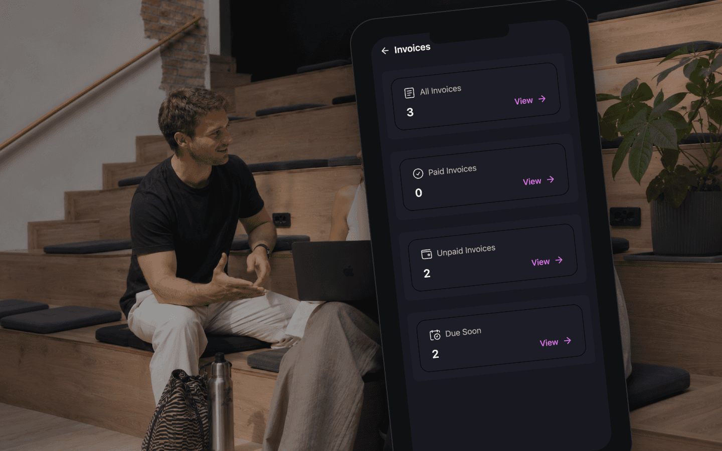 A phone on the amphitheatre steps showing the invoices summary in the member app